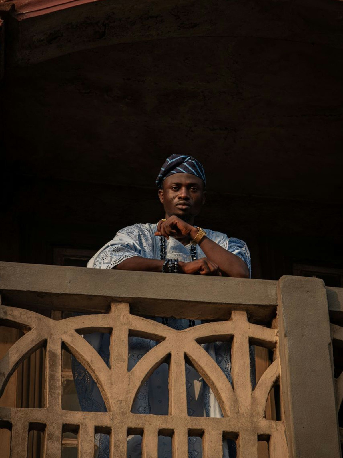 An African man in native attire standing in reflection at golden hour