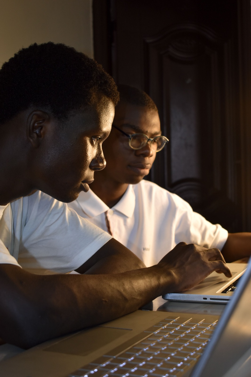 An older African man mentoring a younger man in quiet conversation, natural light